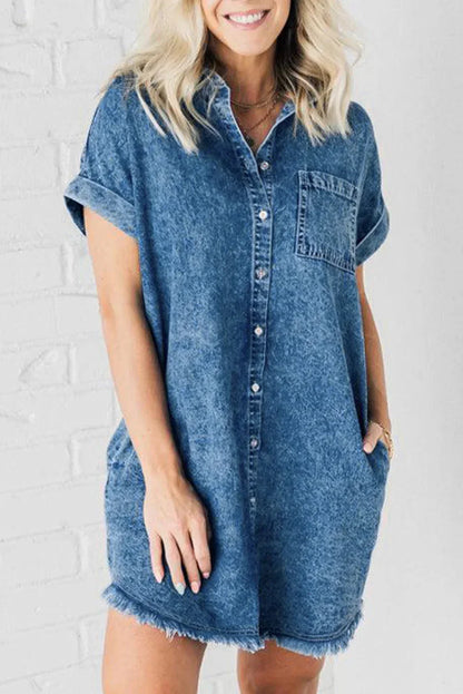 Woman wearing a relaxed fit mottled wash denim mini shirt dress with rolled short sleeves, a button-front closure, and a frayed raw hem.