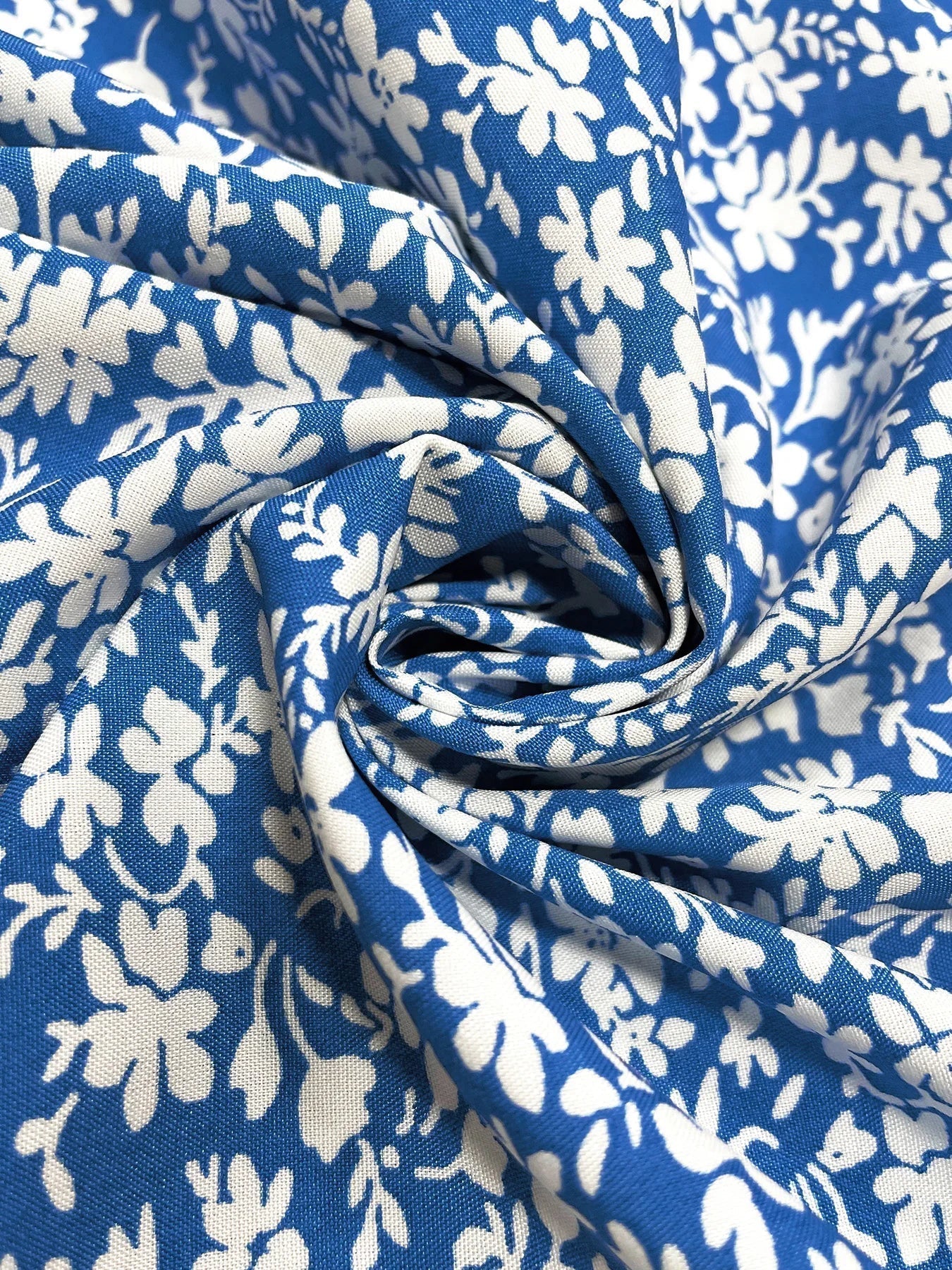 Green - A woman wearing a blue and white ditsy floral print midi dress with puff sleeves, a square neck with a ruched bust tie, and a high thigh slit, holding a small white handbag.