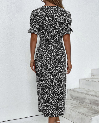 Red - A woman wearing a blue and white ditsy floral midi dress featuring a V-neckline, ruched side detailing with white buttons, and short puff sleeves with ruffled cuffs.
