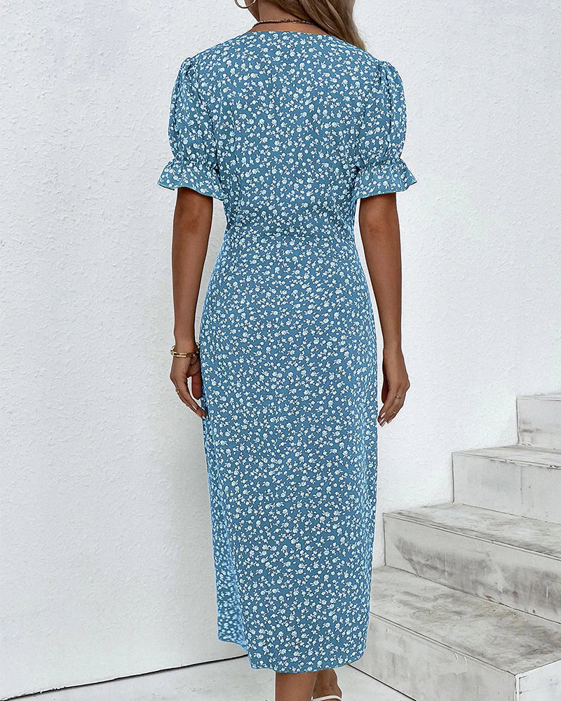 Blue - A woman wearing a blue and white ditsy floral midi dress featuring a V-neckline, ruched side detailing with white buttons, and short puff sleeves with ruffled cuffs.