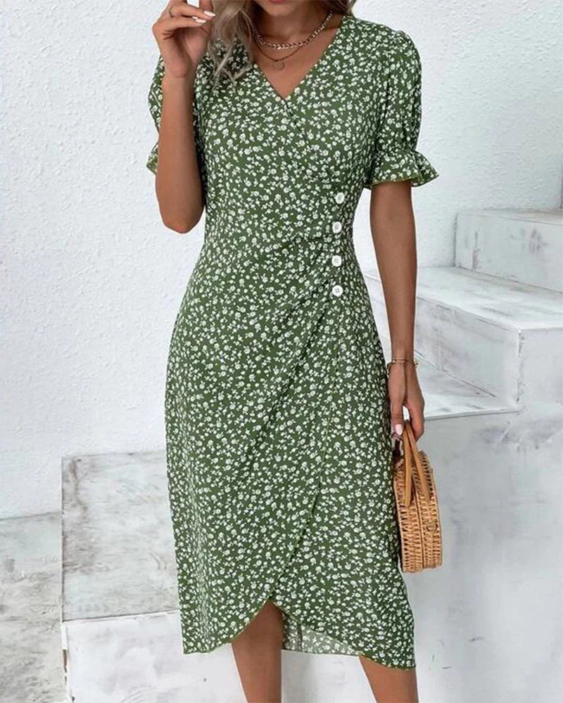 Green - A woman wearing a blue and white ditsy floral midi dress featuring a V-neckline, ruched side detailing with white buttons, and short puff sleeves with ruffled cuffs.