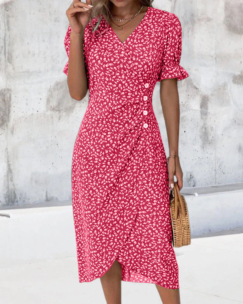 Red - A woman wearing a blue and white ditsy floral midi dress featuring a V-neckline, ruched side detailing with white buttons, and short puff sleeves with ruffled cuffs.