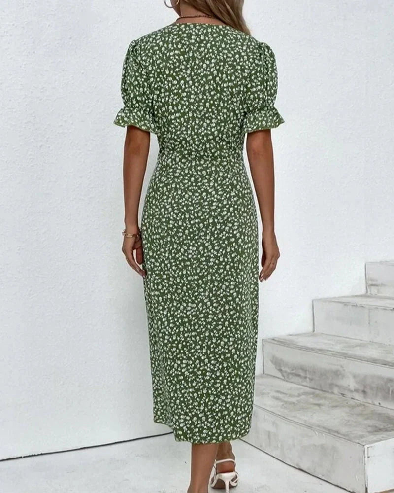 Red - A woman wearing a blue and white ditsy floral midi dress featuring a V-neckline, ruched side detailing with white buttons, and short puff sleeves with ruffled cuffs.