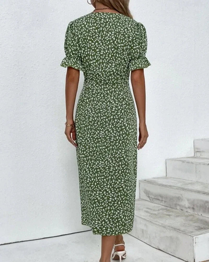 Red - A woman wearing a blue and white ditsy floral midi dress featuring a V-neckline, ruched side detailing with white buttons, and short puff sleeves with ruffled cuffs.