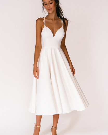 White - A woman wearing a structured white textured crepe midi dress with double spaghetti straps, a sweetheart neckline, and a flared A-line skirt.