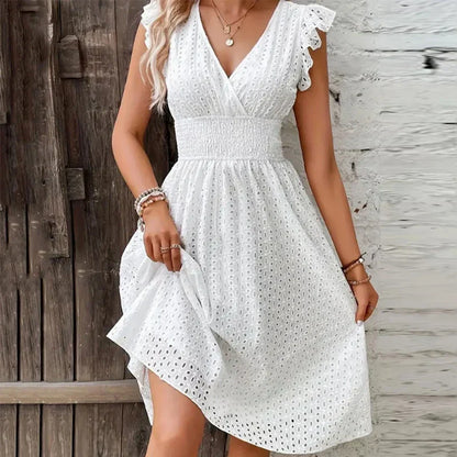 White - A woman wearing a white eyelet midi dress with flutter sleeves, a surplice V-neckline, and a wide smocked waistband, standing against a rustic wooden door.
