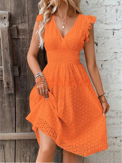 Orange - A woman wearing a white eyelet midi dress with flutter sleeves, a surplice V-neckline, and a wide smocked waistband, standing against a rustic wooden door.