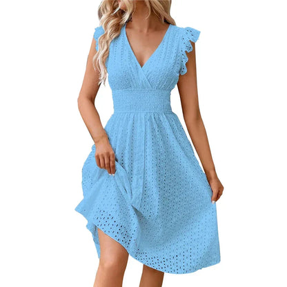Blue - A woman wearing a white eyelet midi dress with flutter sleeves, a surplice V-neckline, and a wide smocked waistband, standing against a rustic wooden door.
