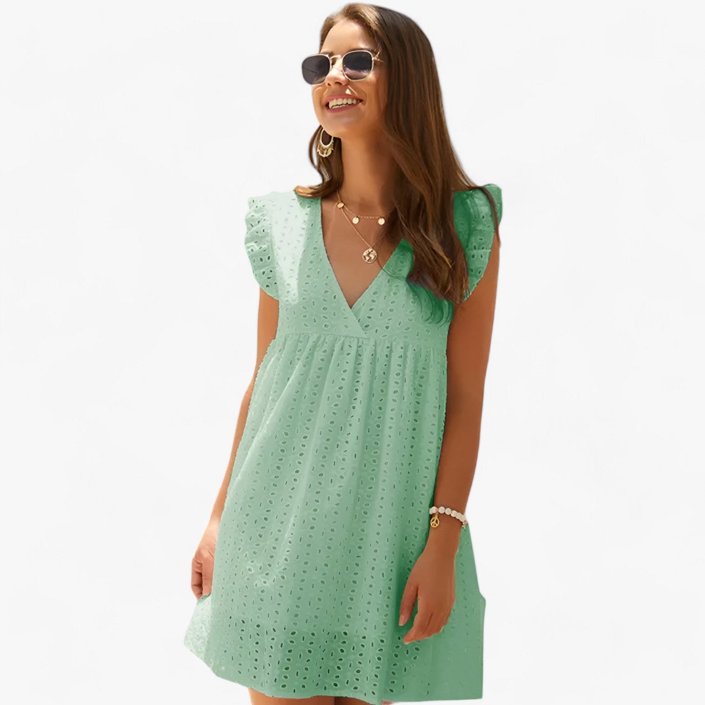 Mint Green - A woman smiling in a black eyelet mini dress with flutter sleeves, a deep V-neckline, and an empire waist, set against a clean white background.