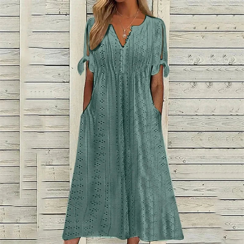 PEACOCK GREEN - A woman wearing a light blue midi-length eyelet dress with a scalloped V-neckline, split tie-sleeves, and side pockets, shown alongside color variations in pink, white, and mint green.