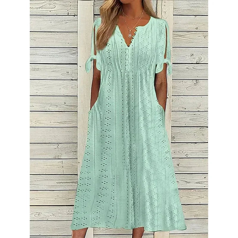 A woman wearing a light blue midi-length eyelet dress with a scalloped V-neckline, split tie-sleeves, and side pockets, shown alongside color variations in pink, white, and mint green.