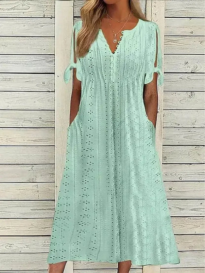 GREEN - A woman wearing a light blue midi-length eyelet dress with a scalloped V-neckline, split tie-sleeves, and side pockets, shown alongside color variations in pink, white, and mint green.