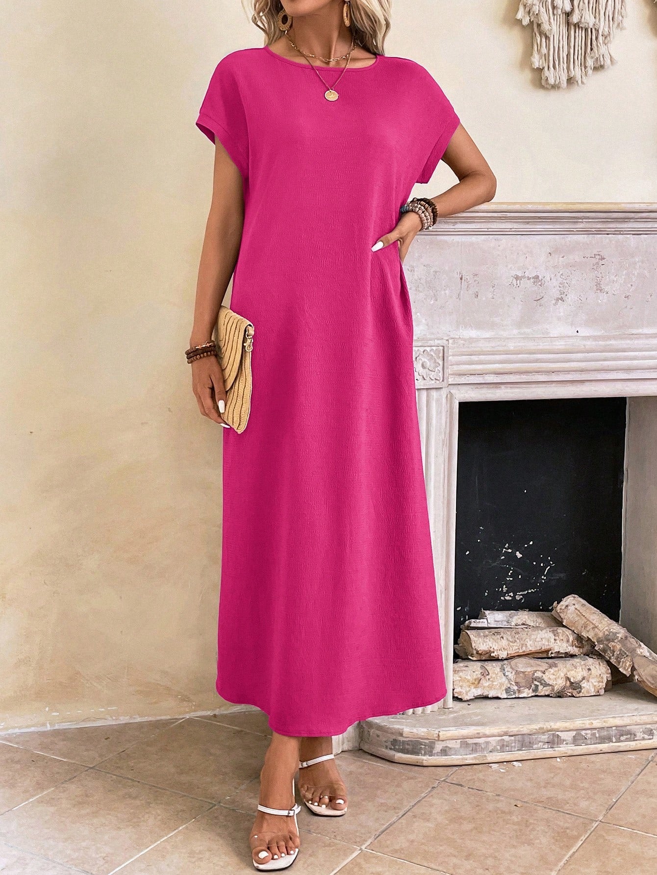 Dark Blue - A woman wearing a beige fine-knit maxi dress with cap sleeves and a crew neck, styled with gold jewelry and a woven clutch in a minimalist interior.