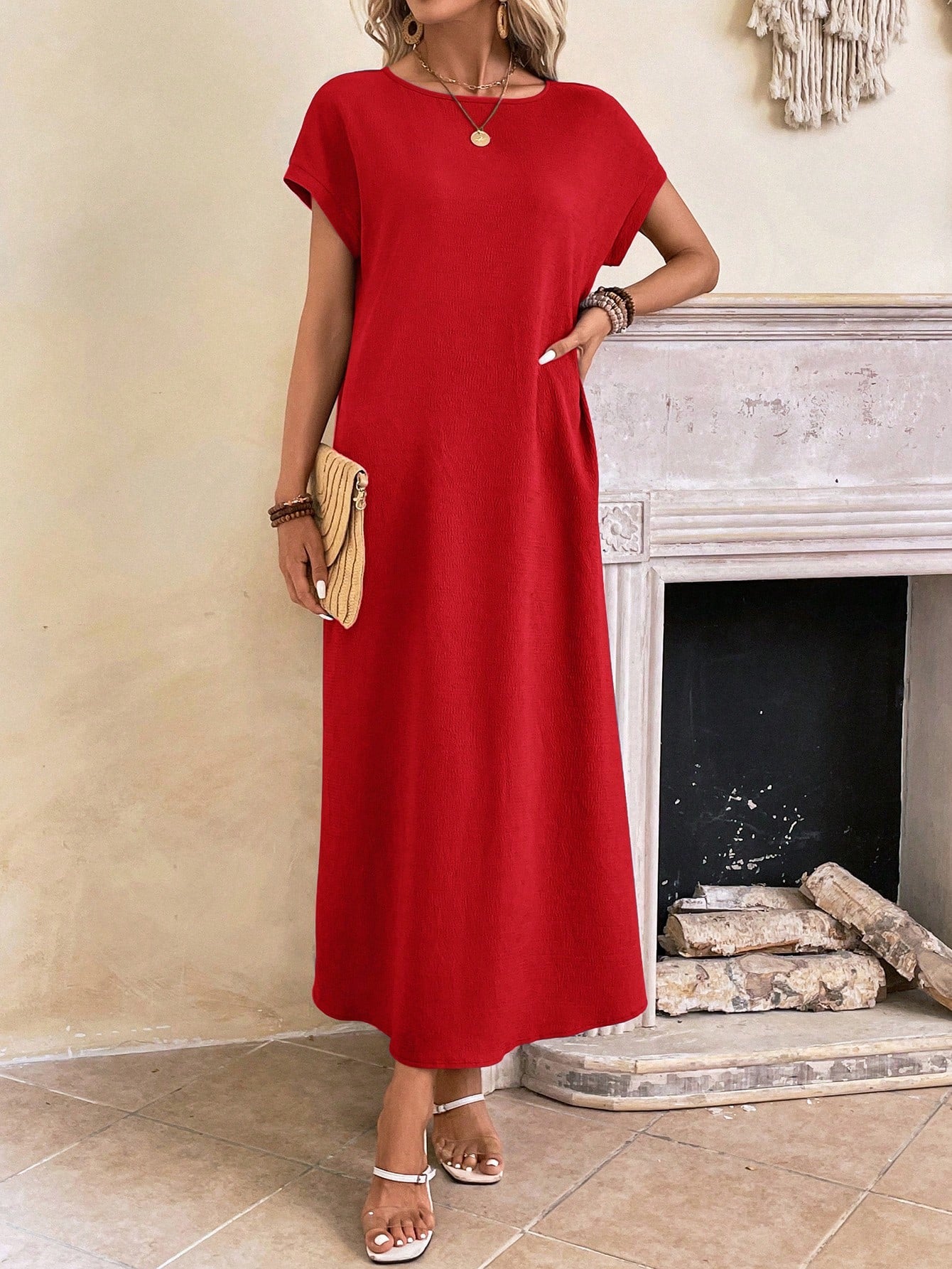Dark Blue - A woman wearing a beige fine-knit maxi dress with cap sleeves and a crew neck, styled with gold jewelry and a woven clutch in a minimalist interior.