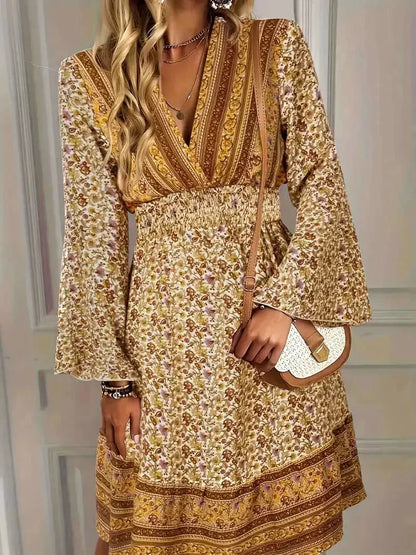 Mixed floral print mini dress in earthy mustard and brown tones featuring a deep V-neckline, wide smocked waist, and long bell sleeves.