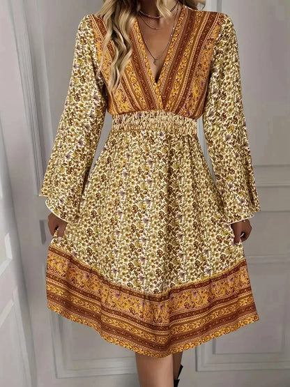 Mixed floral print mini dress in earthy mustard and brown tones featuring a deep V-neckline, wide smocked waist, and long bell sleeves.