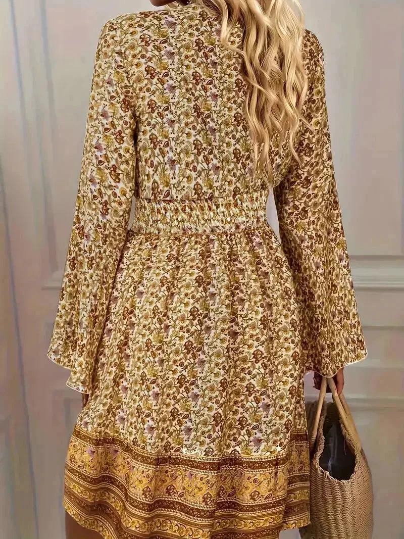 Mixed floral print mini dress in earthy mustard and brown tones featuring a deep V-neckline, wide smocked waist, and long bell sleeves.