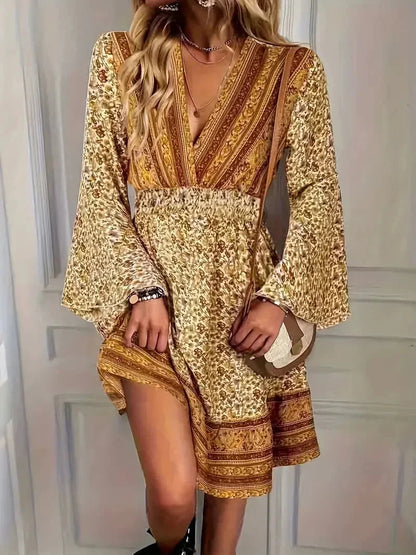 Boho - Mixed floral print mini dress in earthy mustard and brown tones featuring a deep V-neckline, wide smocked waist, and long bell sleeves.