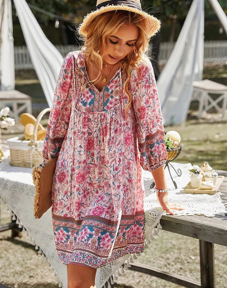 Pink - Women's lightweight mini dress featuring a warm-toned floral border print, split tie neckline, and long blouson sleeves in a relaxed babydoll silhouette.