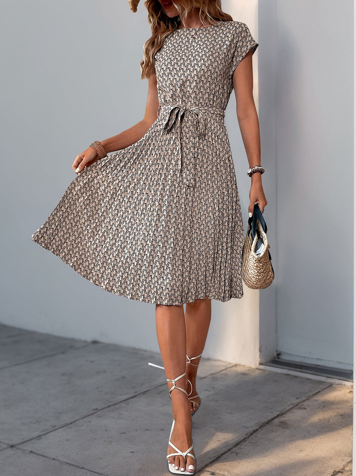 Khaki - Woman wearing a lightweight floral cap sleeve midi dress with a tie waist and pleated skirt.