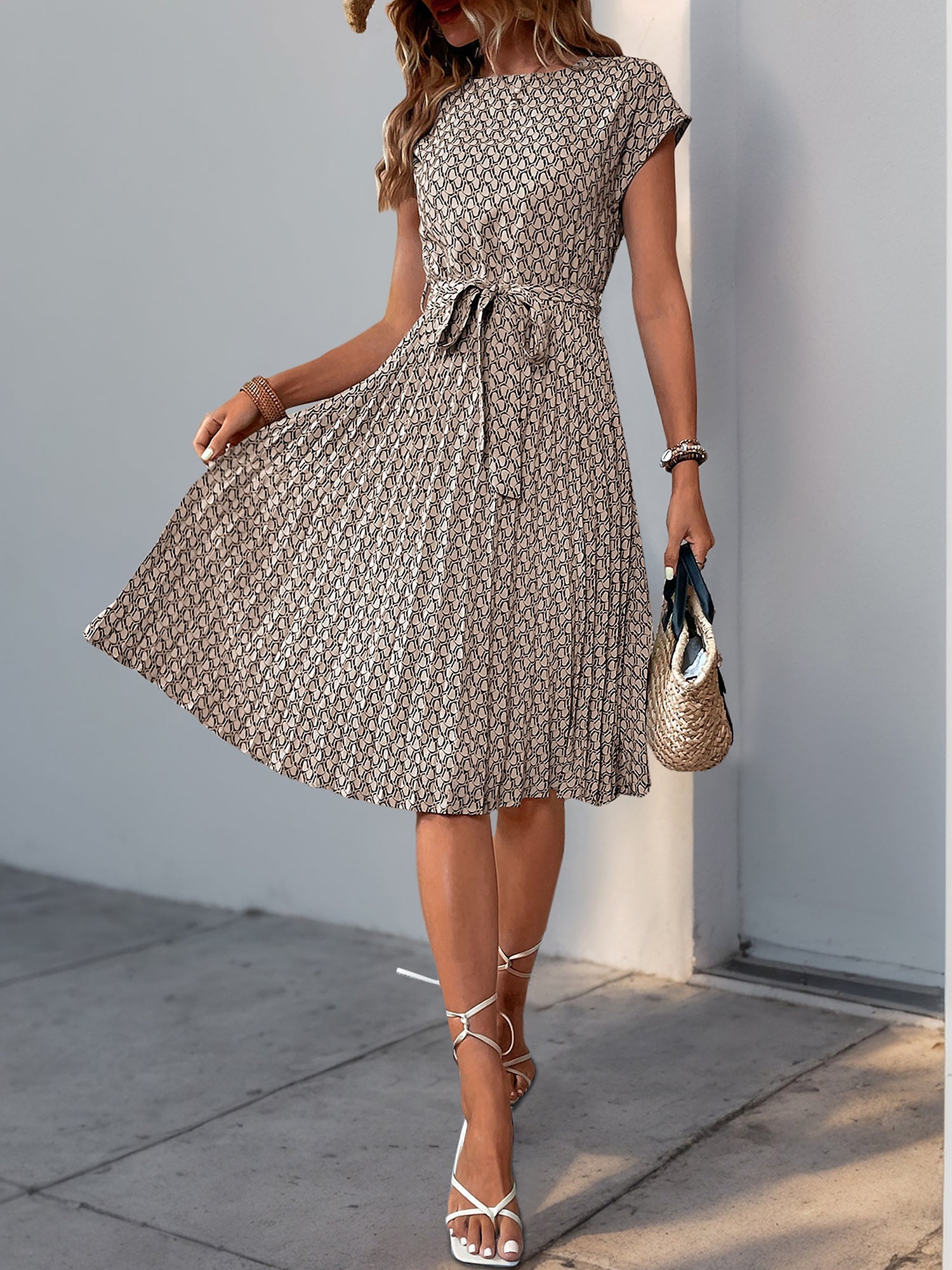 Khaki - Woman wearing a lightweight floral cap sleeve midi dress with a tie waist and pleated skirt.