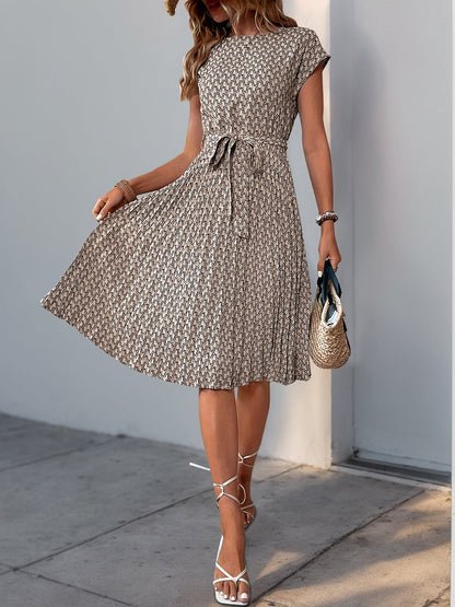 Khaki - Woman wearing a lightweight floral cap sleeve midi dress with a tie waist and pleated skirt.