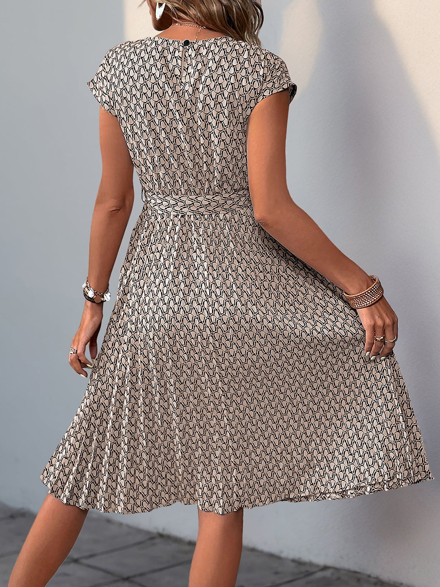 Khaki - Woman wearing a lightweight floral cap sleeve midi dress with a tie waist and pleated skirt.
