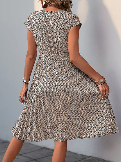 Khaki - Woman wearing a lightweight floral cap sleeve midi dress with a tie waist and pleated skirt.