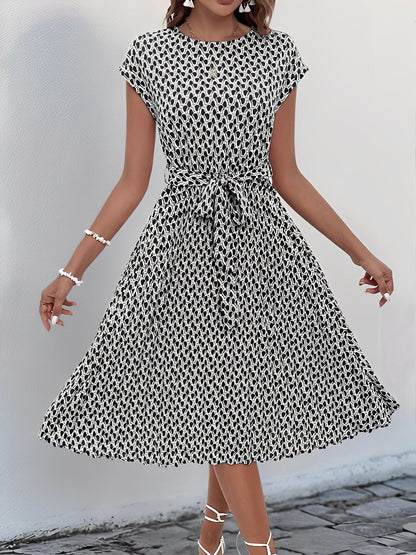 Black - Woman wearing a lightweight floral cap sleeve midi dress with a tie waist and pleated skirt.