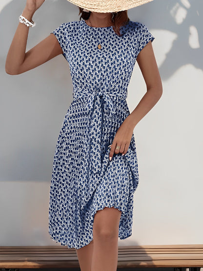 Navy Blue - Woman wearing a lightweight floral cap sleeve midi dress with a tie waist and pleated skirt.
