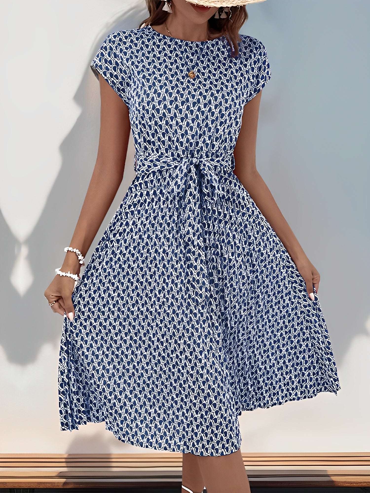 Navy Blue - Woman wearing a lightweight floral cap sleeve midi dress with a tie waist and pleated skirt.