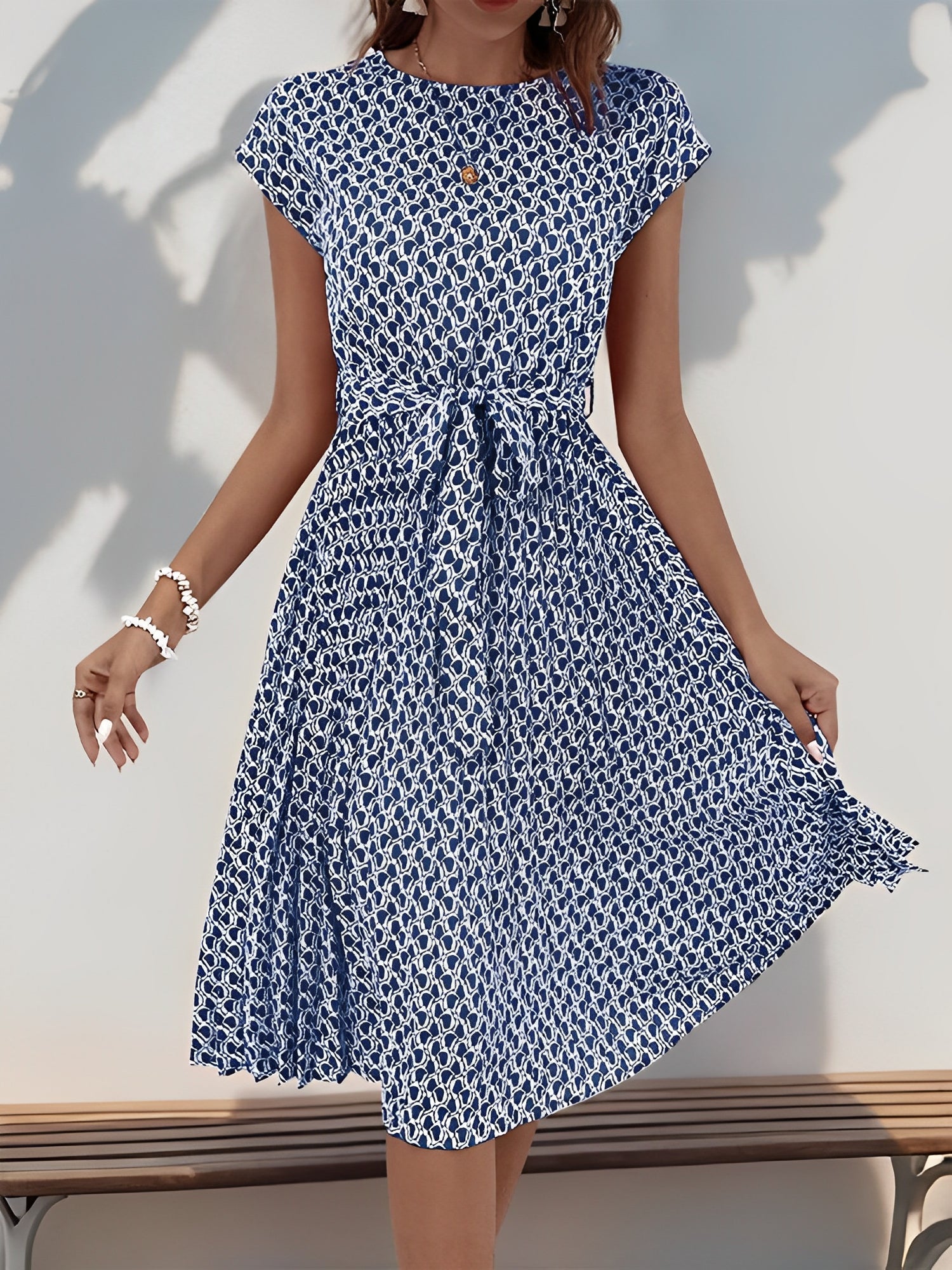 Navy Blue - Woman wearing a lightweight floral cap sleeve midi dress with a tie waist and pleated skirt.