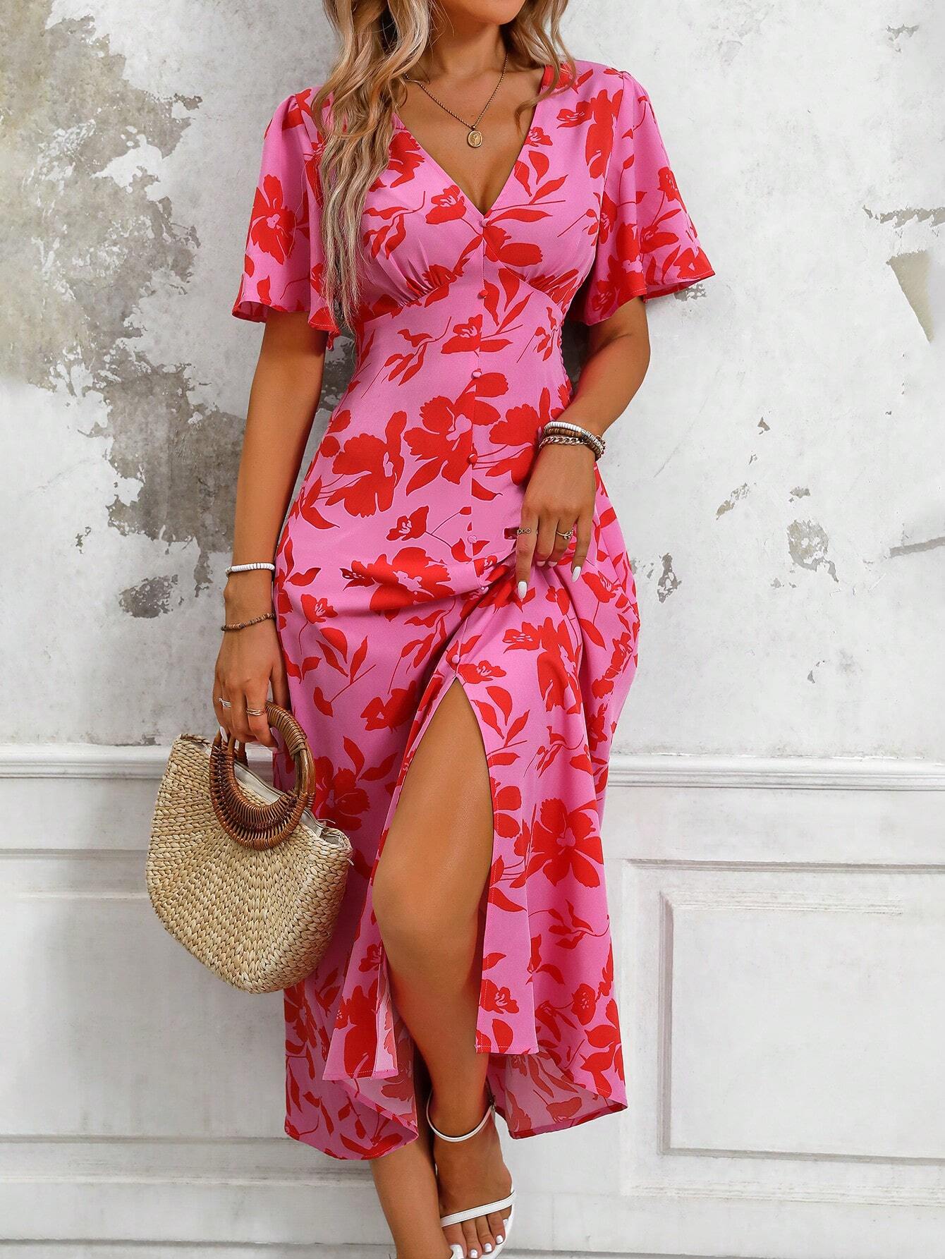 Pink - A woman wearing a pink and red floral print maxi dress with flutter sleeves, a V-neckline, button-front detailing, and a high front slit, holding a woven straw handbag.