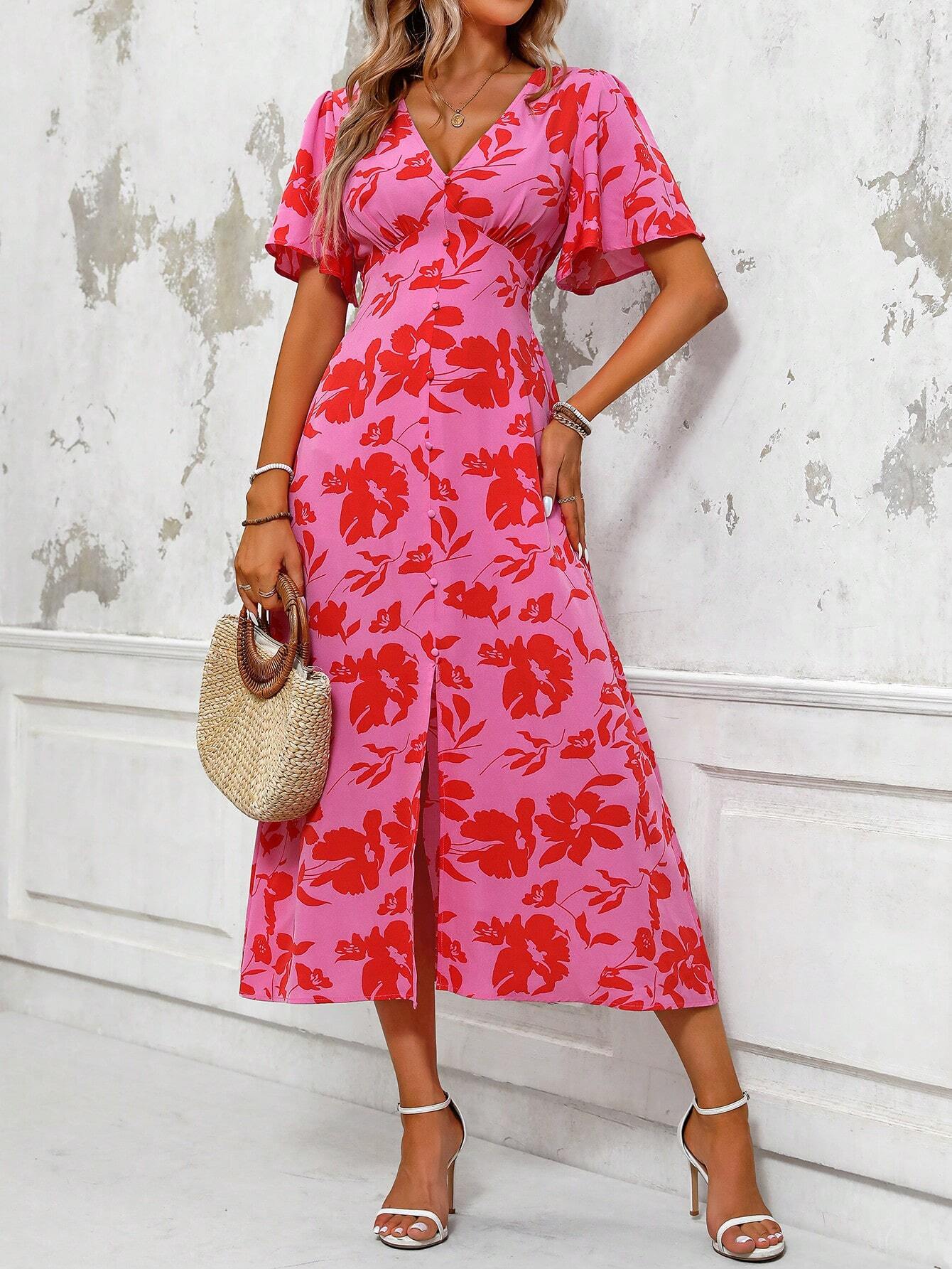 Pink - A woman wearing a pink and red floral print maxi dress with flutter sleeves, a V-neckline, button-front detailing, and a high front slit, holding a woven straw handbag.