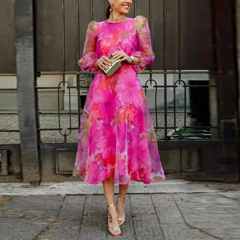 Hot Pink - Woman wearing a vibrant pink floral chiffon midi dress with sheer puff sleeves and an A-line skirt, walking outdoors holding a gold clutch.