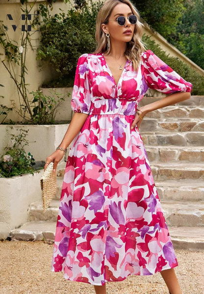 Pink - Woman wearing a multicolored abstract floral chiffon midi dress with a V-neckline, elbow-length puff sleeves, and a smocked waist, standing outdoors on stone steps.