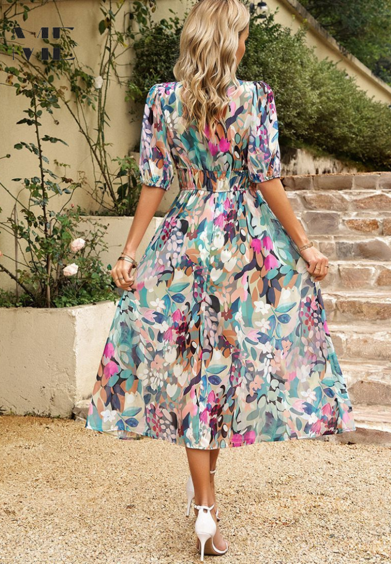 Pink - Woman wearing a multicolored abstract floral chiffon midi dress with a V-neckline, elbow-length puff sleeves, and a smocked waist, standing outdoors on stone steps.