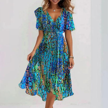 A woman wearing a dark green chiffon midi dress with a white ditsy floral print, featuring flutter sleeves, a surplice V-neckline, a self-tie waist, and a flowing curved hem.