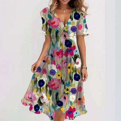 Floral - A woman wearing a dark green chiffon midi dress with a white ditsy floral print, featuring flutter sleeves, a surplice V-neckline, a self-tie waist, and a flowing curved hem.