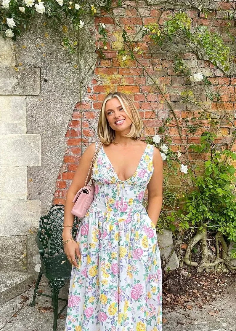 White - Woman wearing a white midi dress with yellow and pink floral print, featuring a corset-style bodice and a full gathered skirt.