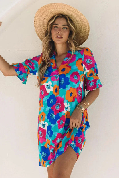 Blue - Woman wearing a vibrant teal mini shift dress with large abstract pink, orange, and blue floral print, featuring a split neckline and flutter sleeves.