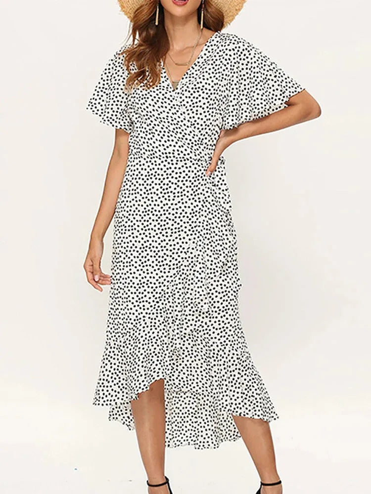 White - Woman modeling a floral print short sleeve wrap maxi dress featuring a tie waist and asymmetrical ruffled hemline.