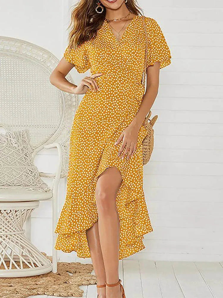Yellow - Woman modeling a floral print short sleeve wrap maxi dress featuring a tie waist and asymmetrical ruffled hemline.