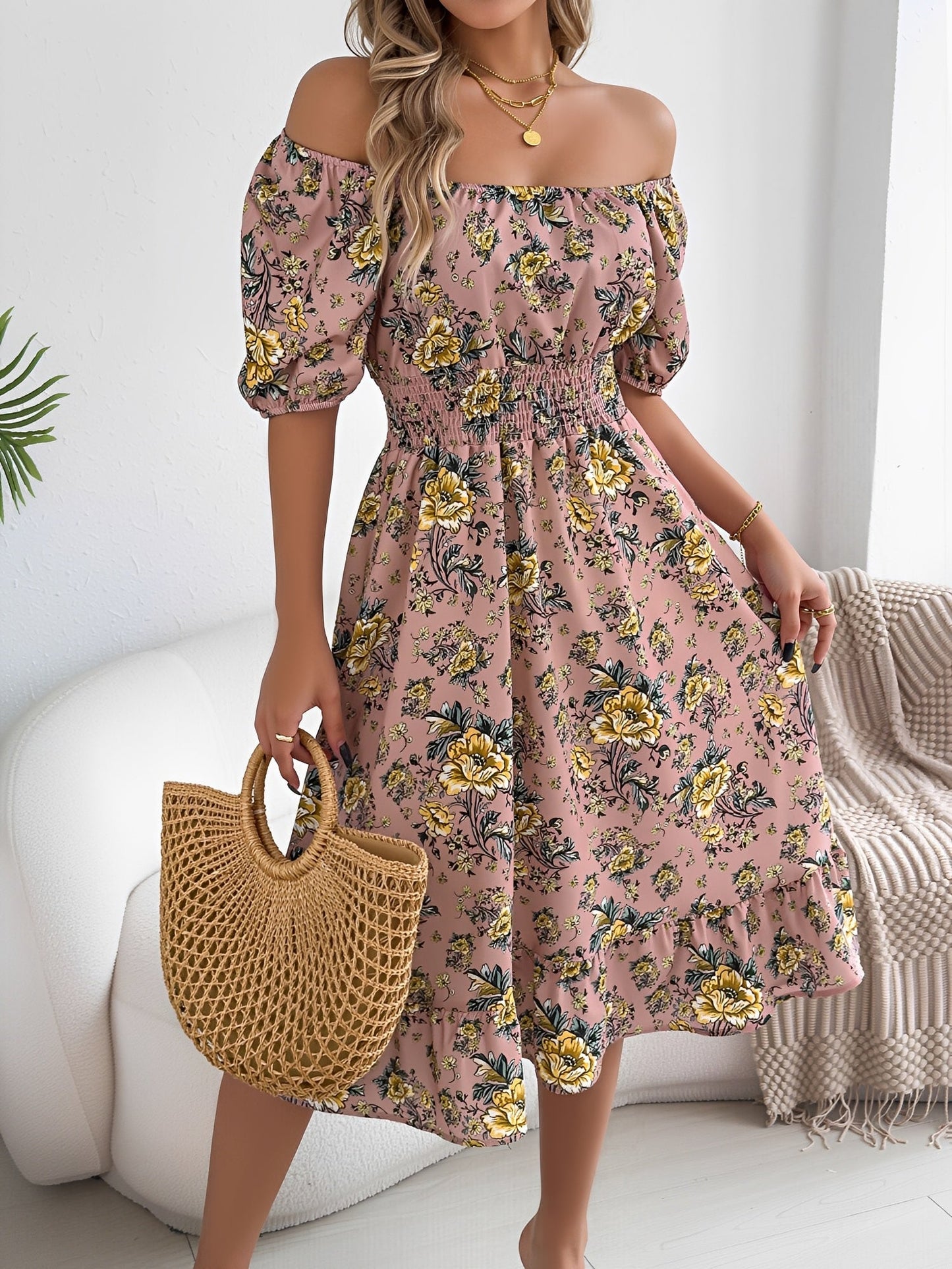 Pink - Woman wearing a floral off-shoulder midi dress with puff sleeves, a smocked waist, and a ruffle hem, holding a woven straw bag