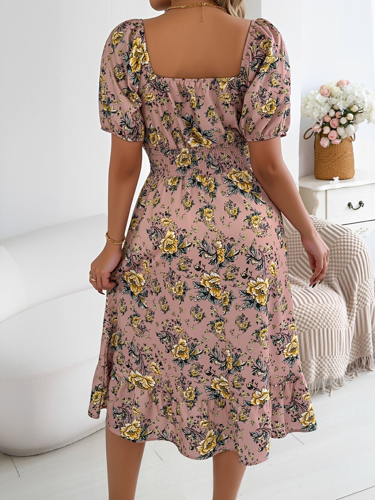 Pink - Woman wearing a floral off-shoulder midi dress with puff sleeves, a smocked waist, and a ruffle hem, holding a woven straw bag