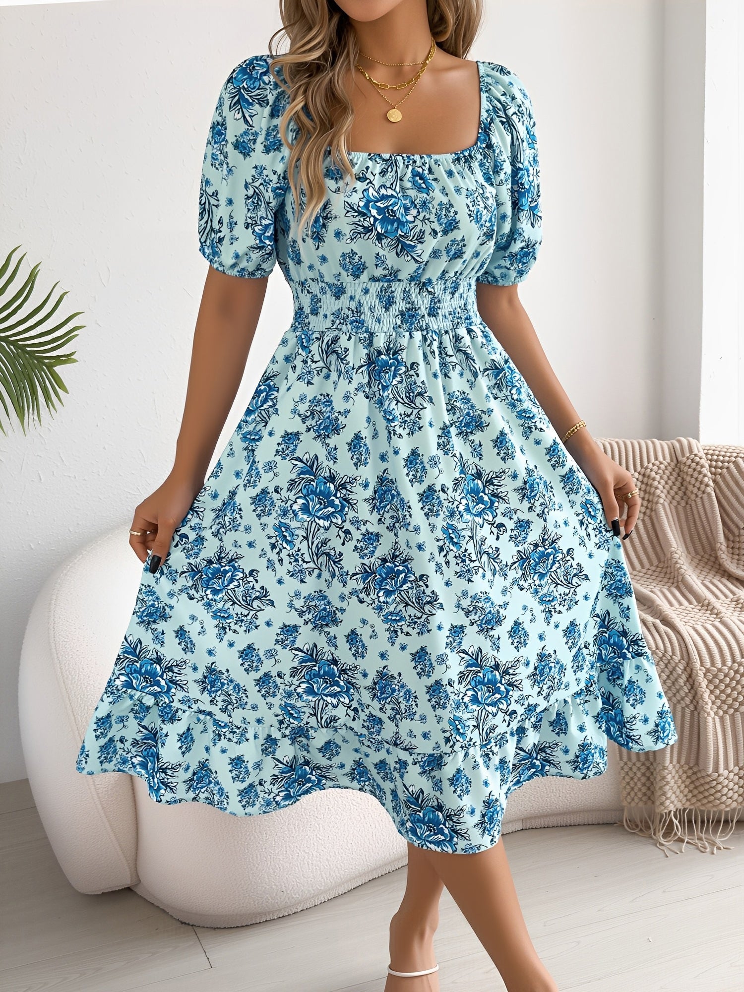 Blue - Woman wearing a floral off-shoulder midi dress with puff sleeves, a smocked waist, and a ruffle hem, holding a woven straw bag