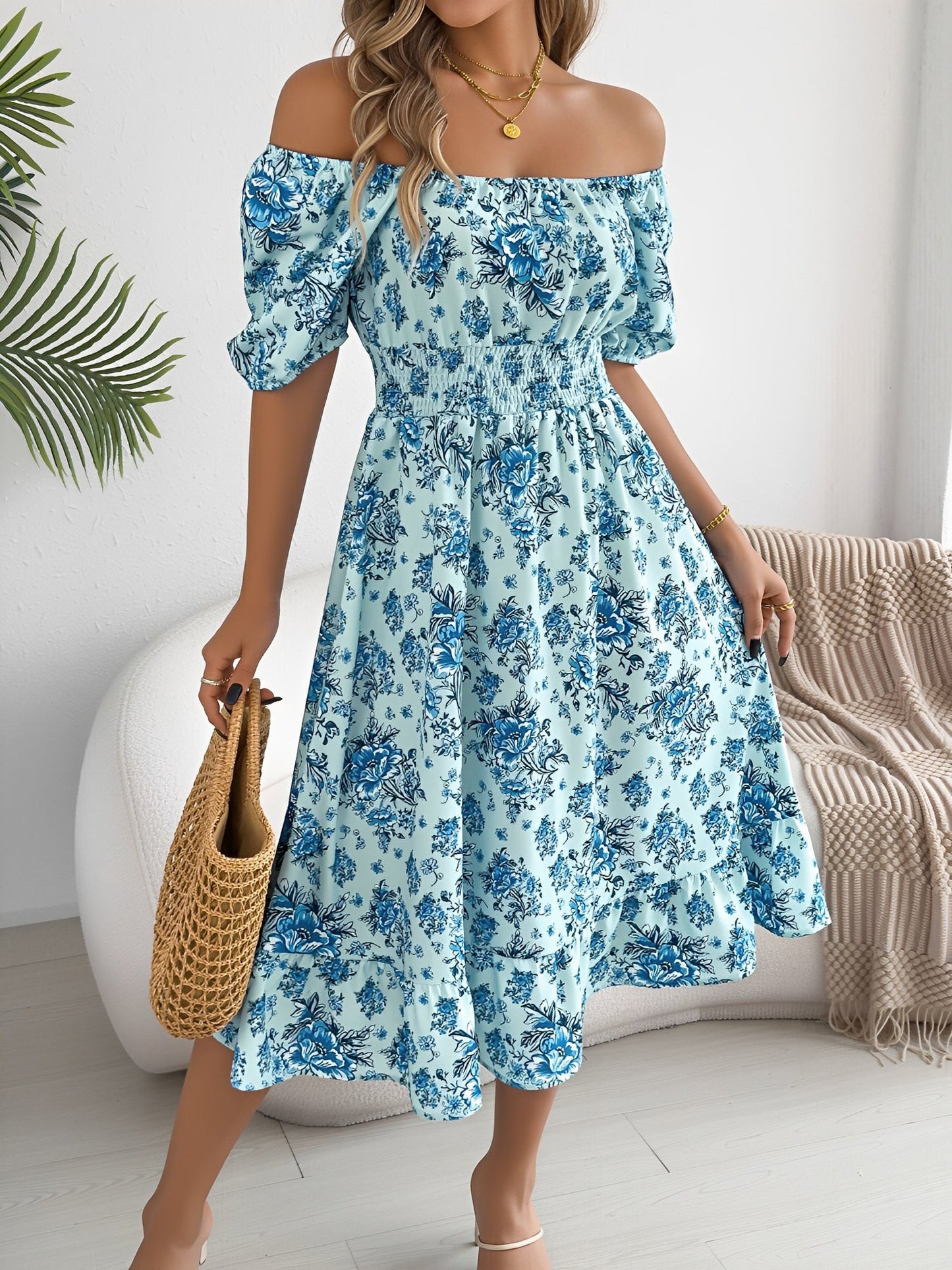 Blue - Woman wearing a floral off-shoulder midi dress with puff sleeves, a smocked waist, and a ruffle hem, holding a woven straw bag
