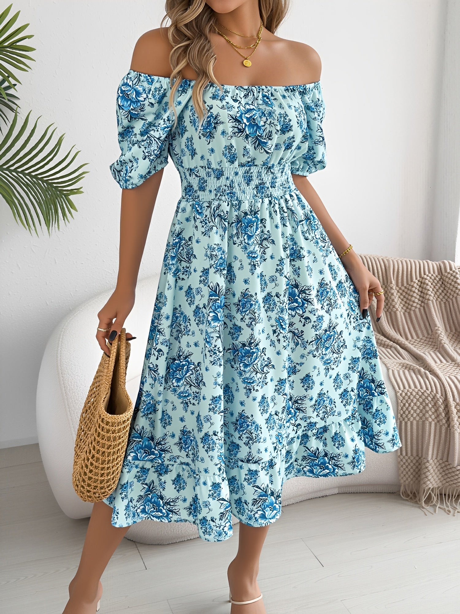 Blue - Woman wearing a floral off-shoulder midi dress with puff sleeves, a smocked waist, and a ruffle hem, holding a woven straw bag