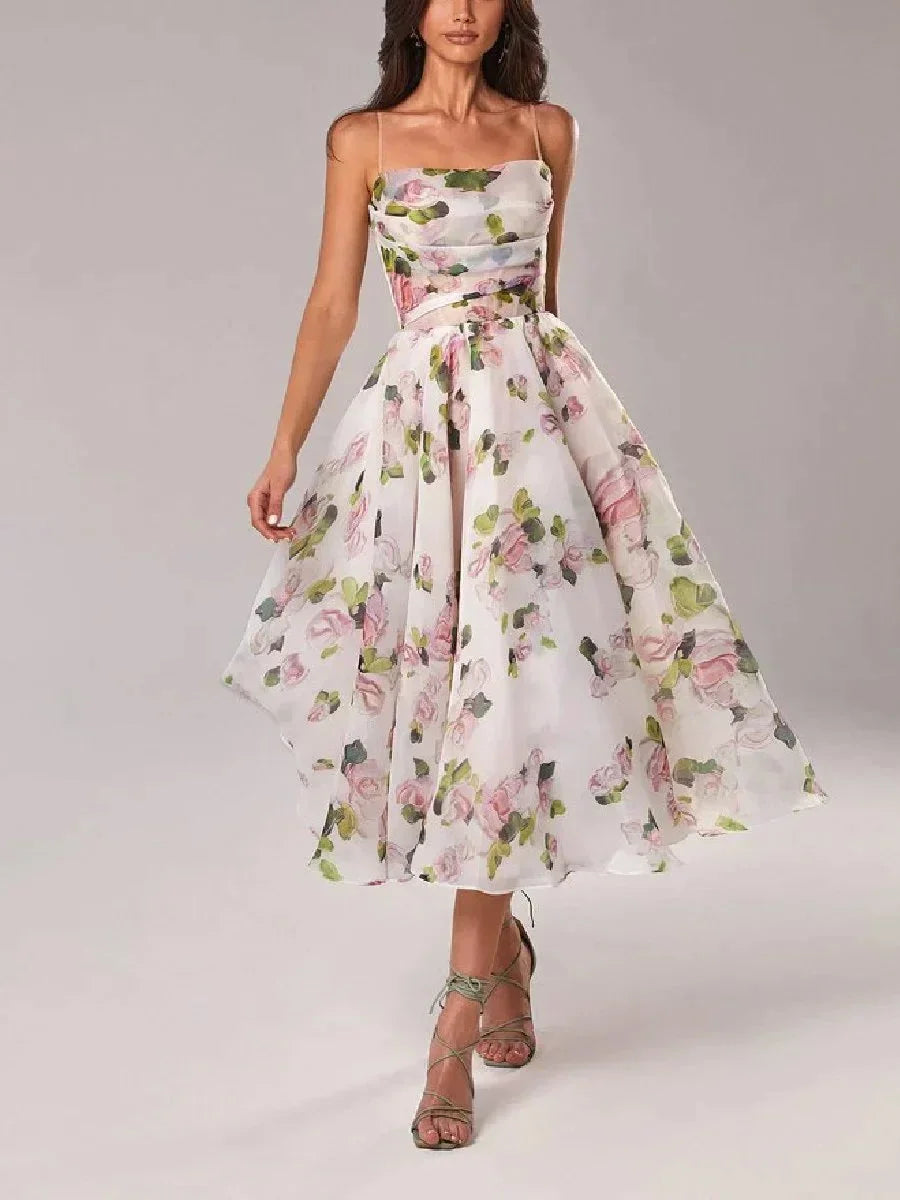 White midi dress with pink and green floral print, featuring a ruched bodice, spaghetti straps, and a full A-line skirt.