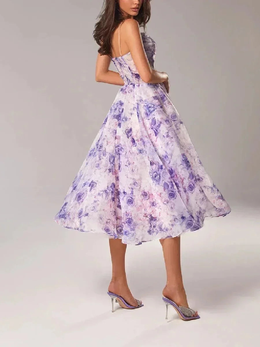 White midi dress with pink and green floral print, featuring a ruched bodice, spaghetti straps, and a full A-line skirt.